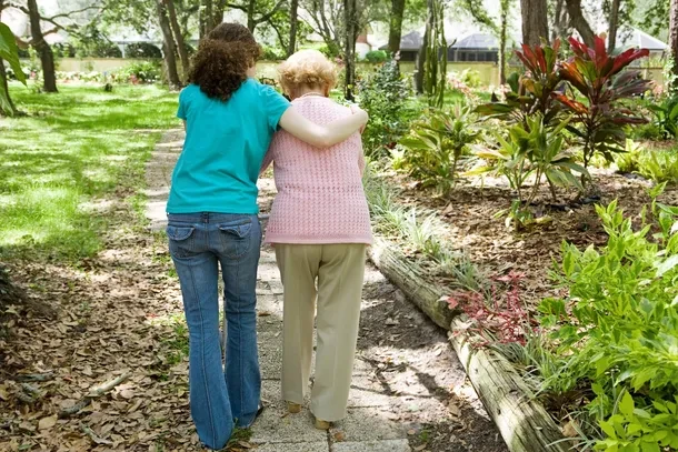Two people walking together in a garden, arms around each other